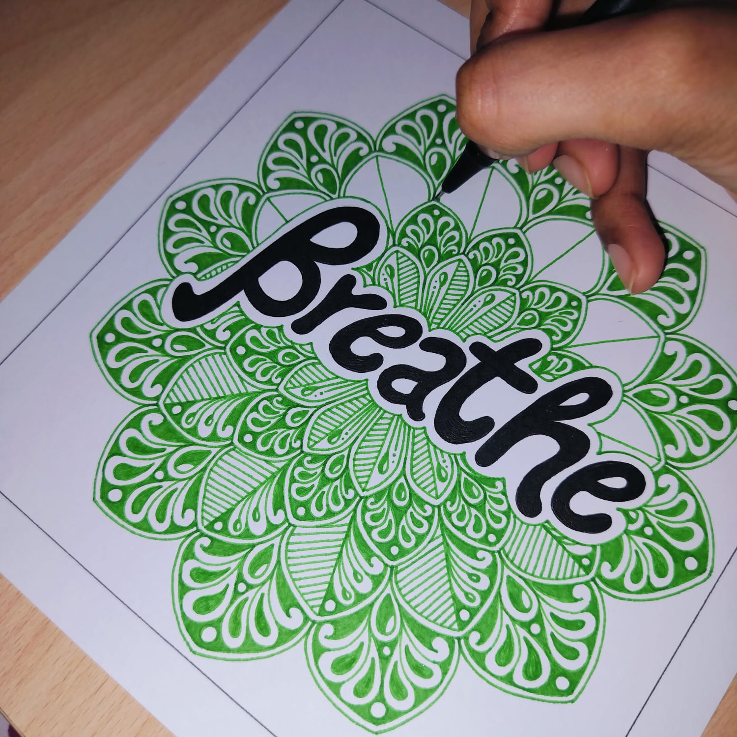 Artist drawing a green Breathe mandala by hand